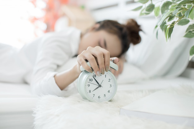 woman asleep in bed while her alarm shows the early time at home in bedroom