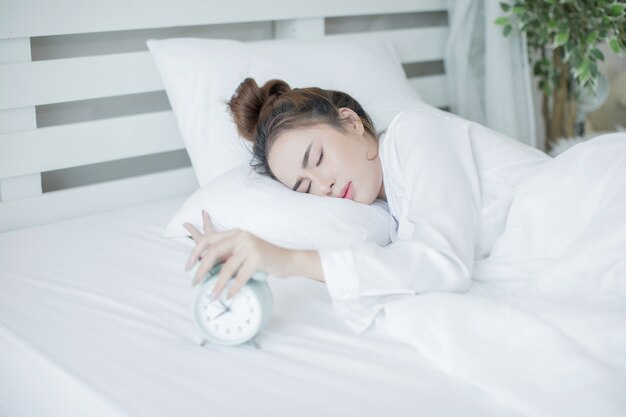 woman asleep in bed while her alarm shows the early time at home in bedroom