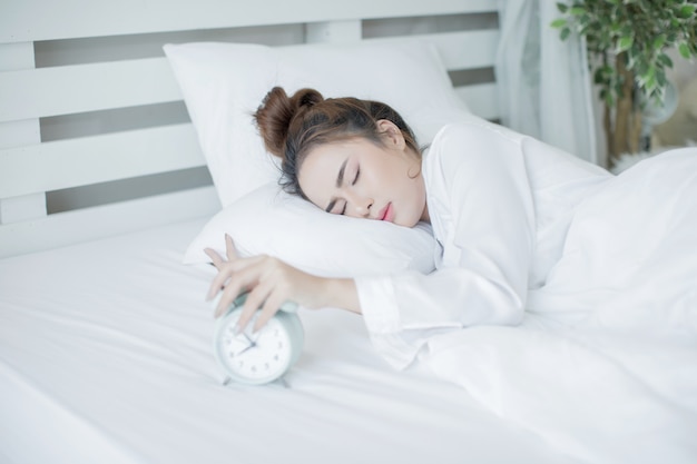Женщина спит в постели, а ее будильник показывает раннее время дома в спальне