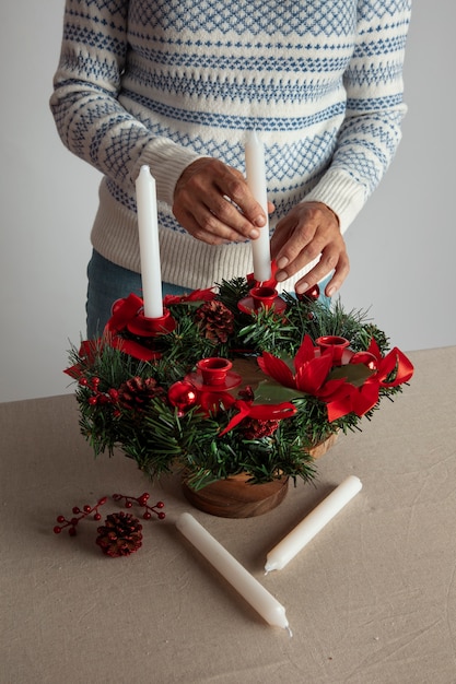Foto gratuita donna che assembla una ghirlanda a tema natalizio