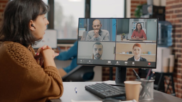 Woman attending business meeting on video call with workmates to discuss about project planning and strategy. Employee doing teamwork with colleagues on online video conference.