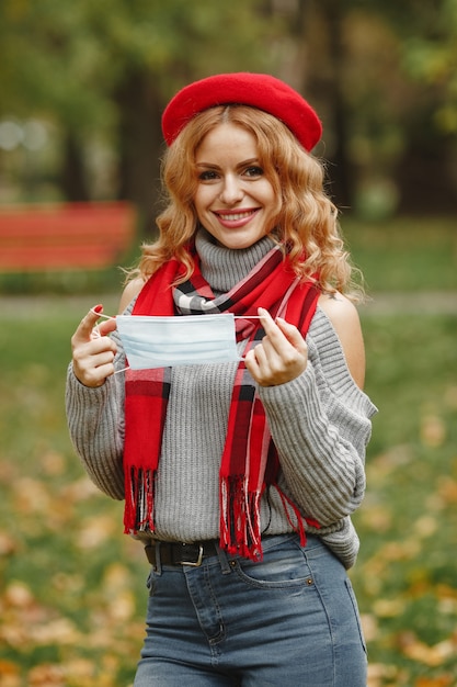 Woman in autumn forest. Person in a mask. Coronavirus theme. Lady in a red scarf.