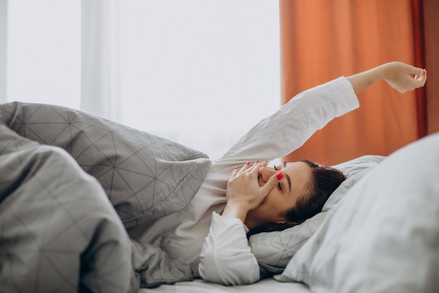 Woman awake stretching in her bed in the morning