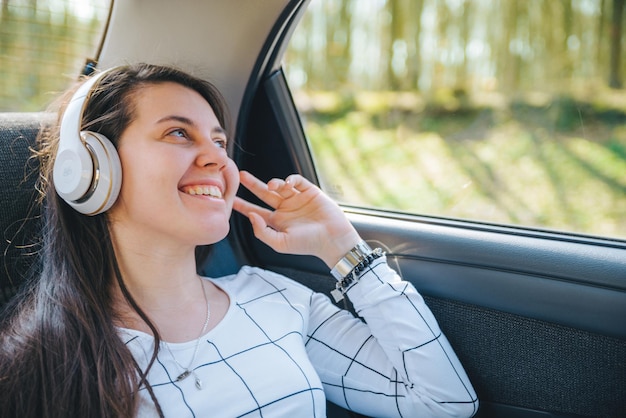 Woman on back seat of car. car travel concept. listing music with headset.
