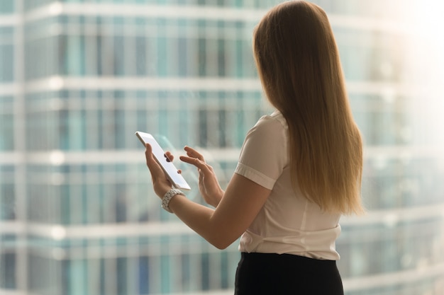 Free photo woman back view swipe with finger on tablet screen