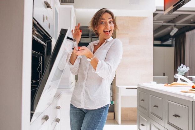 Woman baking at kitchen and looking into the oven