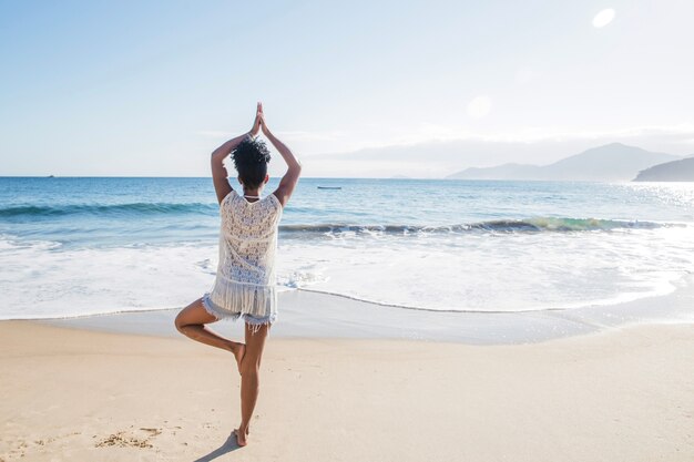 Женщина балансирует на пляже