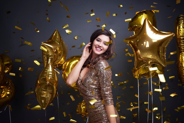 Woman among balloon and confetti falling 
