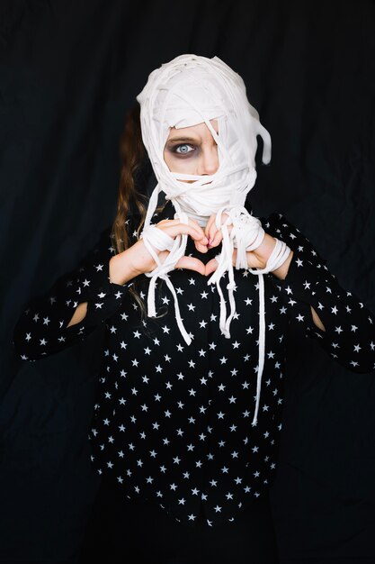 Woman in bandage with heart shaped fingers