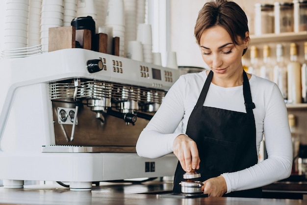 Женщина-бариста в кафе готовит кофе
