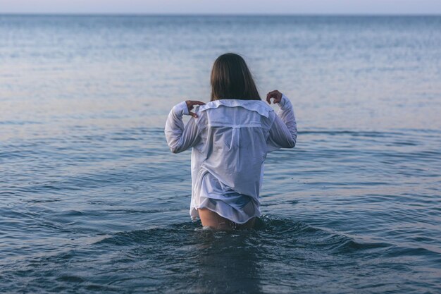 A woman in a bathing suit and a white shirt in the sea