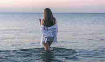 Free photo a woman in a bathing suit and a white shirt in the sea