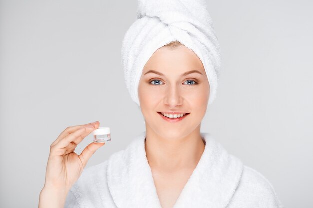 woman in bathrobe showing cream, eye lifting essence