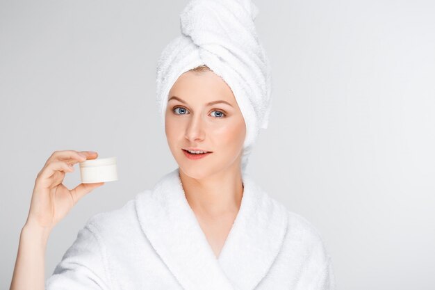 woman in bathrobe showing cream, skincare product promo