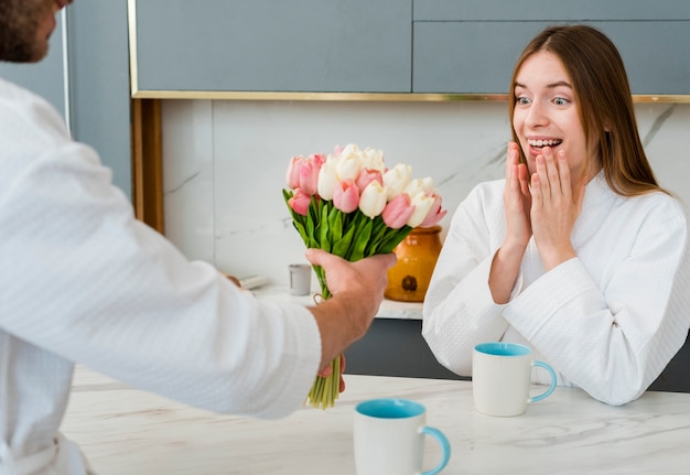 Free photo woman in bathrobe surprised with bouquet of tulips