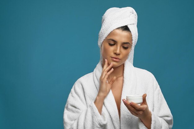 Woman in bathrobe using cream