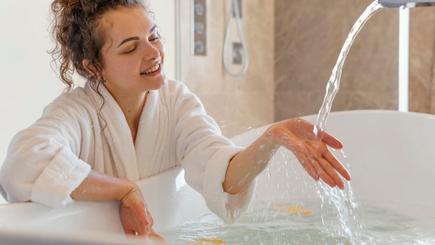 Woman in bathrobe with hand in water