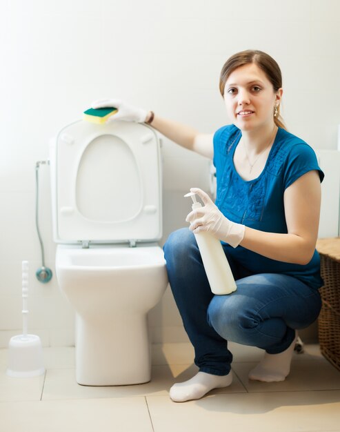 woman in bathroom with sponge and cleaner
