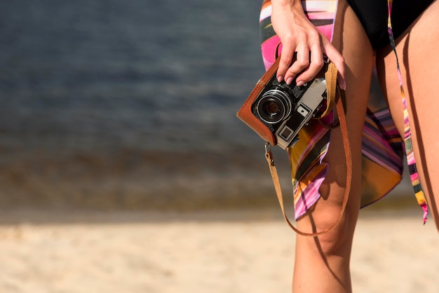 Foto gratuita donna in spiaggia tenendo la fotocamera con copia spazio