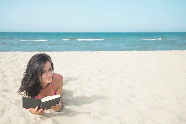 Woman on beach reading a book