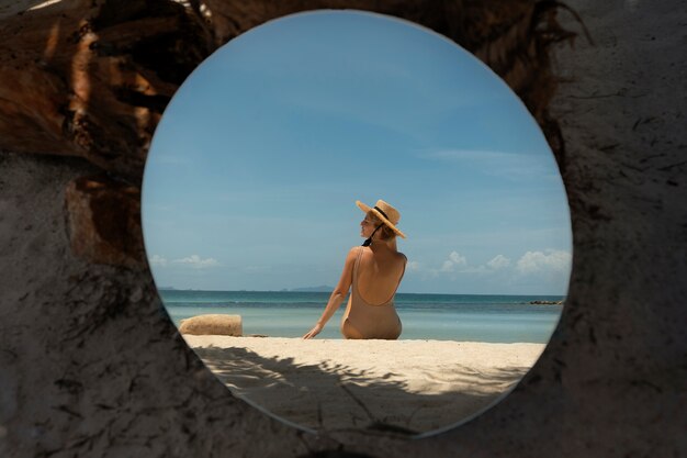 둥근 거울과 함께 포즈를 취하는 여름에 해변에서 여자