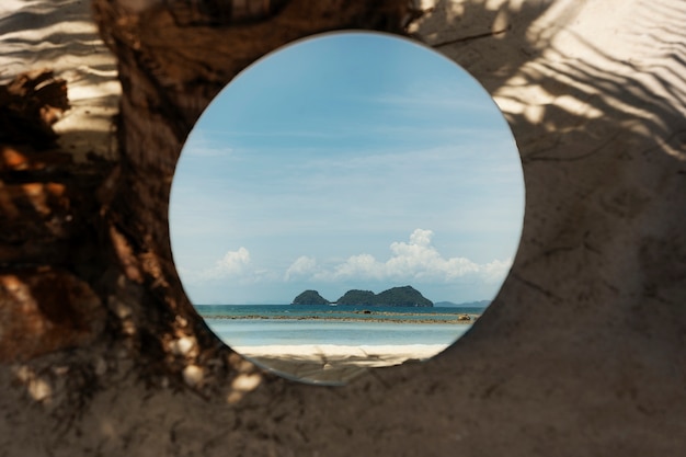 Woman at the beach in summer posing with round mirror