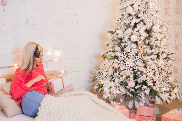 Woman on bed next to christmas tree
