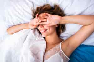 Free photo woman in bed covering her eyes