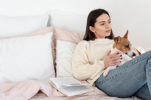 Free photo woman in bed relaxing with her dog