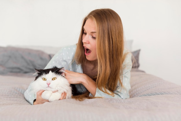 Woman in bed wearing pajamas with cat