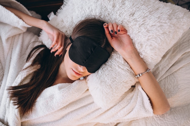 Женщина в кровати носить маску сна