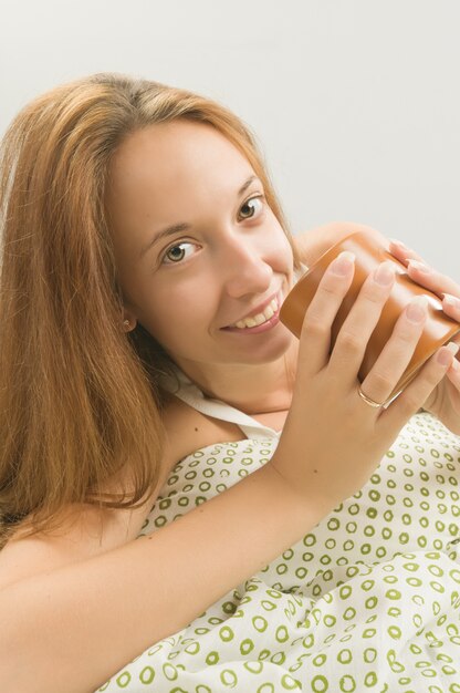 Woman in bed with cup of coffee