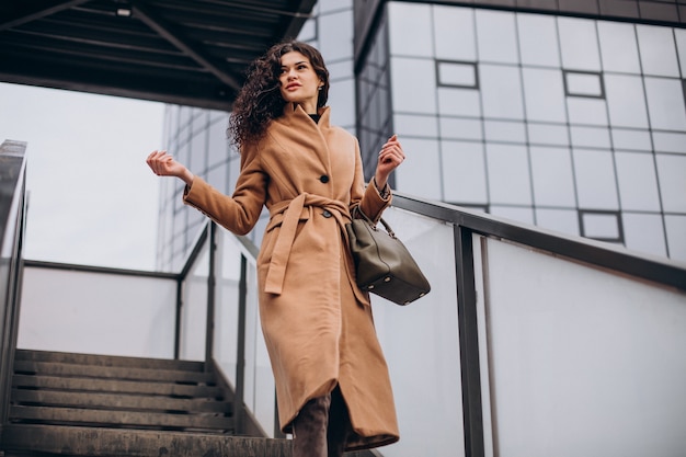 Woman in beige coat walking in the city