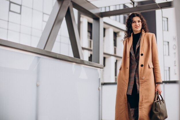 Free photo woman in beige coat walking in the city