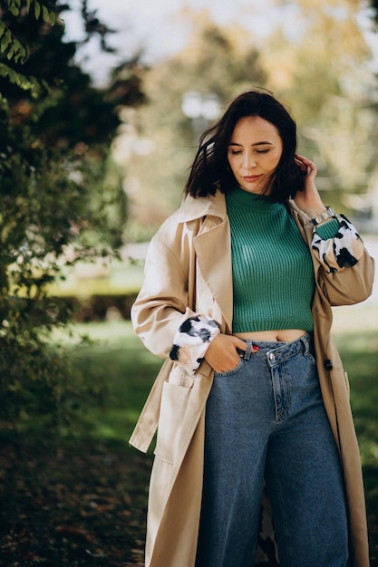 Donna in cappotto beige che cammina nel parco