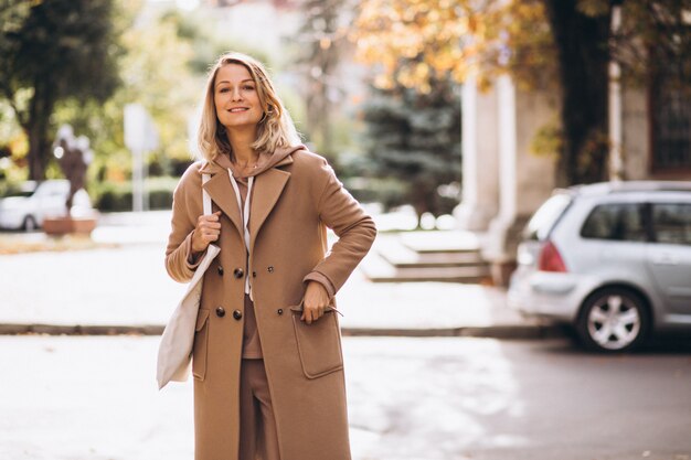 Woman in beige coat with shopping bag in the street