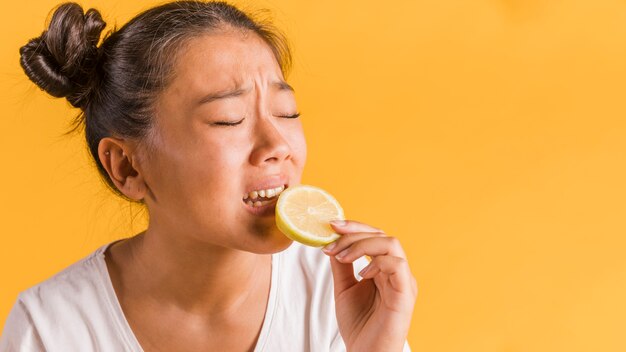 Woman being afraid of biting a lemon