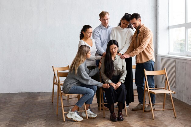 Woman being consoled by people at a group therapy session