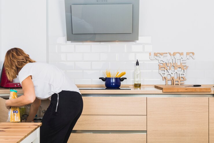 Free Photo woman bending down putting food in cabinet