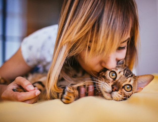 Woman and Bengal cat lie on the bed 