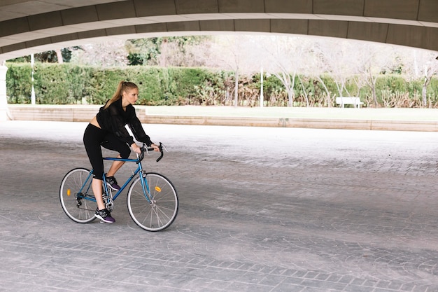 Free photo woman on bicycle under bridge