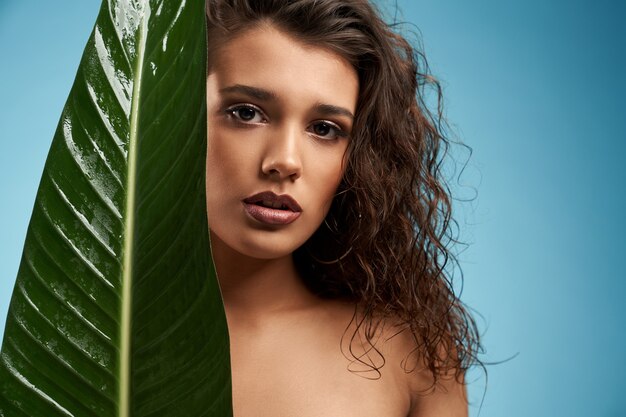 Woman behind big green leaf isolated