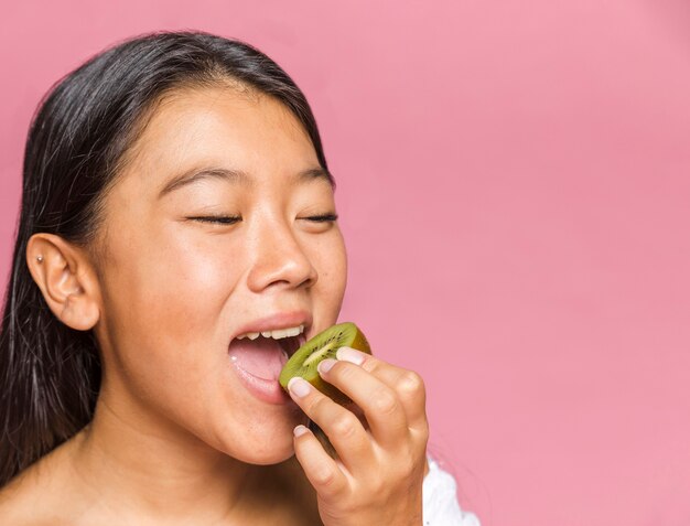 女性はキウイフルーツの半分をかみます