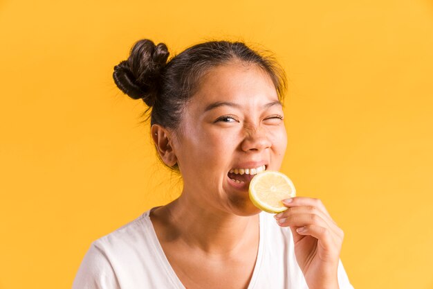 Woman bites a slice of sour lemon