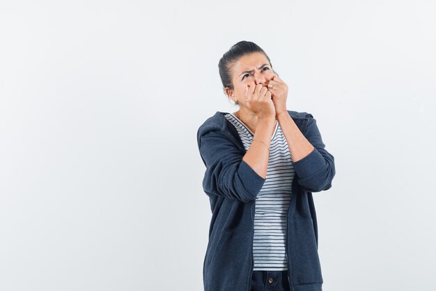 Woman biting fists emotionally in t-shirt