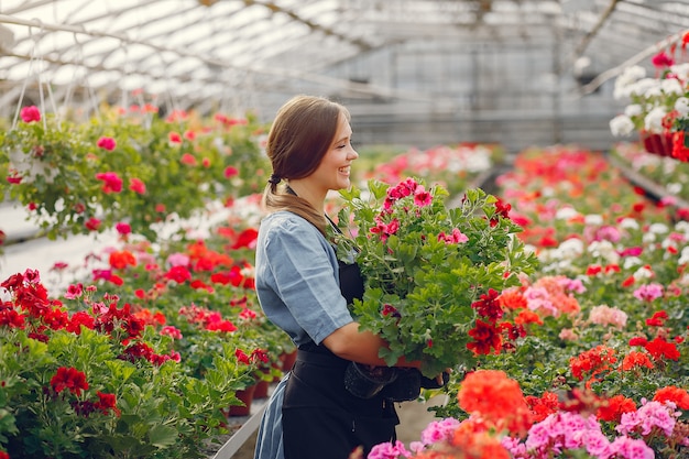 Free photo woman in a black apron working in a greenhouse