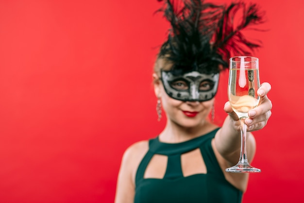 Woman in black carnival mask holding champagne glass