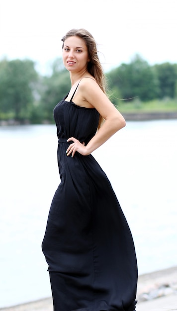 Free photo woman in black dress by the river