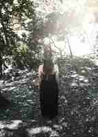 Foto gratuita donna in abito nero e cappello in piedi nella foresta