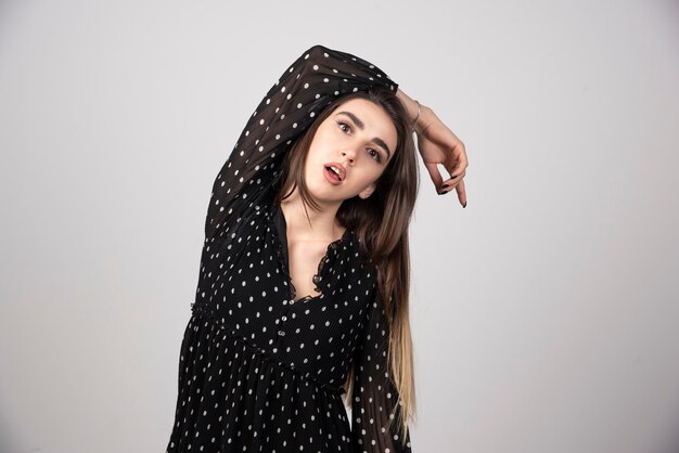 Woman in black dress posing on gray.